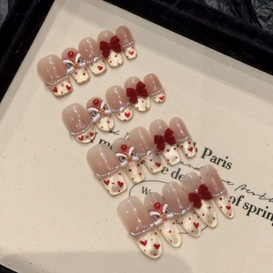 Macro view of handmade press-on nails featuring red 3D bows and lion dance charms