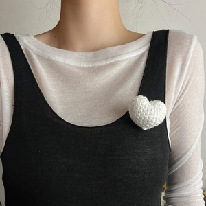 Handmade white knitted heart brooch with 3D texture pinned on black strap clothing