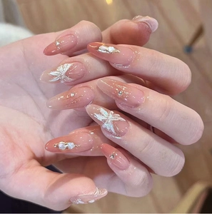 Macro shot of gradient almond nails with 3D floral accents, pearls, and sparkling crystals