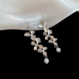 Macro shot of silver textured flower earrings with elegant white pearl tassels