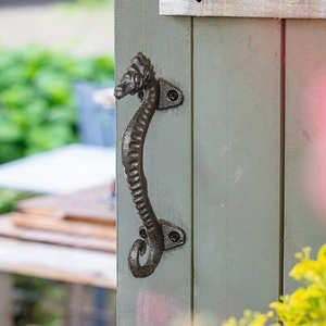 Vintage seahorse cast iron door handle in antique bronze finish on green wooden door