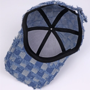 Detailed interior of blue plaid denim baseball cap showing black stitching and frayed edges