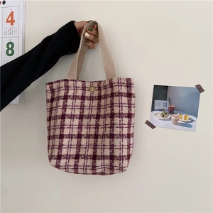 Vintage woolen plaid tote bag with button closure shown hanging against a white wall
