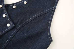 Detailed macro view of dark blue denim fabric with silver metal studs and white stitching