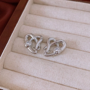 Macro detail of silver snake heart earrings with shimmering cubic zirconia inlay