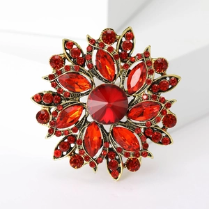 Macro shot of vintage floral brooch with red crystals and antique gold finish on white