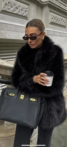 Détail d'un manteau luxueux en fausse fourrure noire avec un sac à main en cuir noir chic