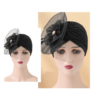 Detailed close-up of a black pleated turban featuring large mesh floral and pearl accents