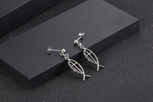 Detail of silver fish-shaped titanium steel earrings featuring Jesus cross engraving