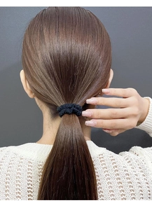 Detail of high-elasticity black fabric scrunchie holding a ponytail on brown hair