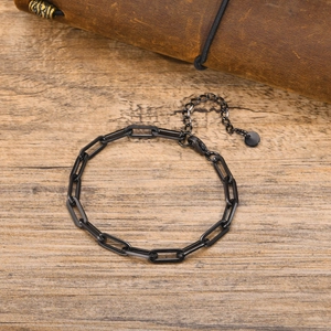 Detail of black geometric rectangle link bracelet with extension chain on wooden surface