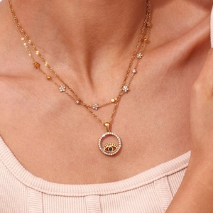 Detail of layered gold titanium necklace featuring evil eye pendant and zircon floral charms