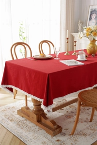 Detail of red rectangle tablecloth featuring delicate white lace edges on wood table
