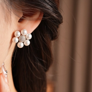 Close-up of a French vintage flower-shaped stud earring with white pearls and zircon