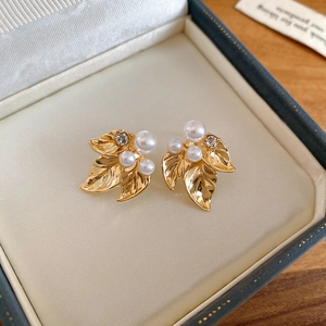 Gros plan de boucles d'oreilles feuille d'or avec perles et cristaux en écrin velours