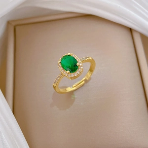 Macro shot of oval green gemstone ring with micro-diamond halo and golden adjustable band