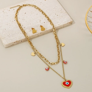 Detail of gold evil eye and heart charms on double layer necklace with matching earrings