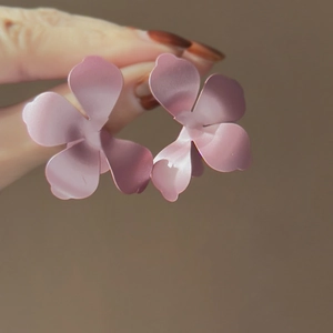 Dettaglio di orecchini a lobo a fiore rosa opaco con design a tre petali lisci