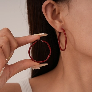 Minimalist deep red twisted wave hoop earrings shown on model for stylish look