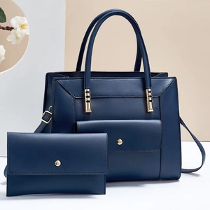 Blue leather tote and clutch bag set with gold hardware on a geometric studio background