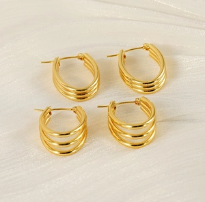 Detail of 18k gold plated triple-layer hoop earrings on cream textured fabric