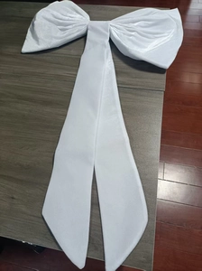 Close-up of a large white velvet decorative bow with ribbons on a wooden surface
