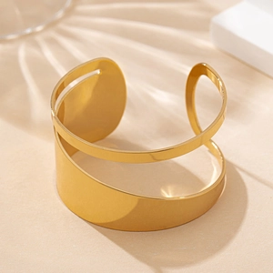Detailed macro shot of irregular hollow gold cuff bracelet on a warm minimalist background