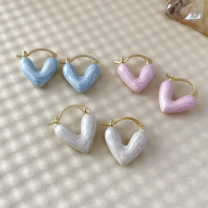 Détail de boucles d'oreilles en forme de cœur bleu clair, rose et blanc, dorées