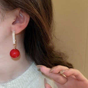 Detail view of a red pearl earring with zircon studs worn on ear, showing elegant texture