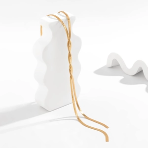 Detail of double-strand gold snake chain necklace with sleek mirror polish on white wave stone