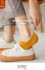 Détail de chaussettes invisibles en coton jaune avec talon en silicone et baskets blanches