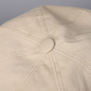 Macro shot of the beige octagonal hat showing twill texture and top button stitching
