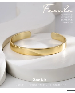 Minimalist gold-plated brass C-shape open cuff bracelet displayed on a geometric pedestal