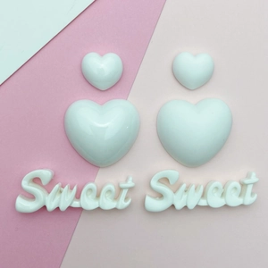 Detailed view of white resin heart and 'Sweet' letter charms for DIY accessories