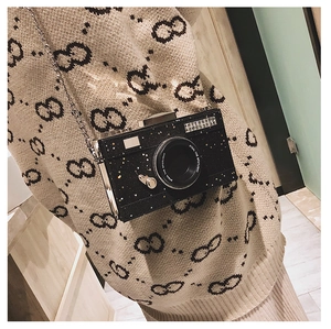 Detail of a vintage black camera-shaped box bag with glitter texture and gold chain strap