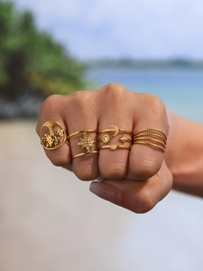 Close-up of four-piece gold bohemian ring set with tree of life and celestial star patterns