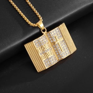 Macro shot of gold-plated holy bible pendant with crystal cross detail and box chain