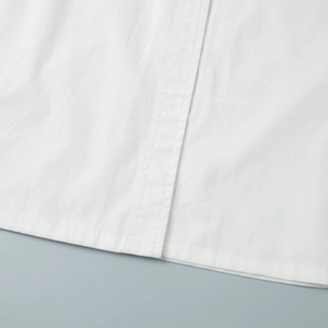 Macro view of tight cotton fabric texture and double-row stitching on white shirt dress