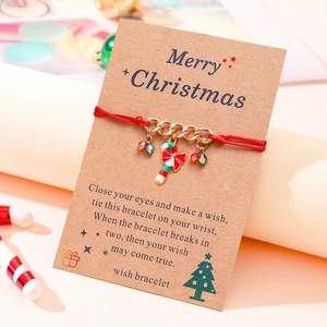 Detail of Christmas wish bracelet with red rope and enamel candy cane charm on kraft card