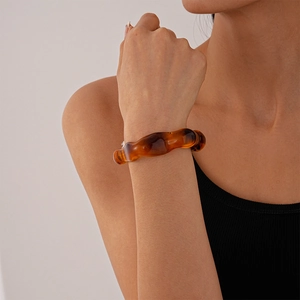 Close-up of amber acrylic irregular wavy bangle with translucent resin texture