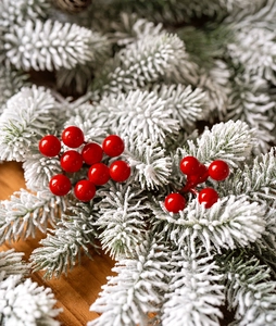 Close-up of artificial pine branch with red berries and realistic snow spray coating