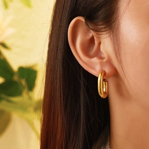 Close-up of minimalist chunky gold-plated titanium steel hoop earrings on model