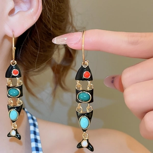 Detailed macro view of fish-shaped drop earrings with black enamel and colored beads