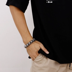 Close-up of a bold silver stainless steel skull link bracelet worn on a male wrist