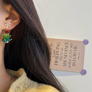 Macro detail of a beaded Christmas tree earring with snowflake top on female model