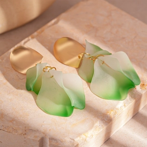Elegant gold metal earrings with gradient green acrylic flower petals on marble