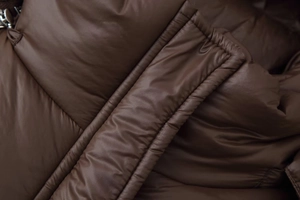 Vue rapprochée du tissu matelassé marron foncé d'une doudoune avec une texture brillante