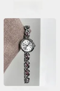 Gros plan d'un bracelet de montre en métal argenté avec pierres ovales violettes et ajouré