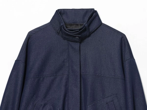 Detail of navy pilot jacket showing stand collar, visible stitching, and durable fabric texture