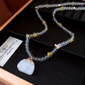 Macro detail of beaded necklace with white agate pendant on a black velvet tray